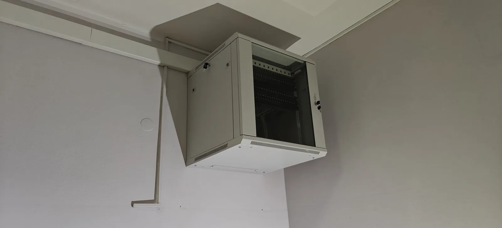 Kompaktowa szafa rack zamontowana wysoko na ścianie